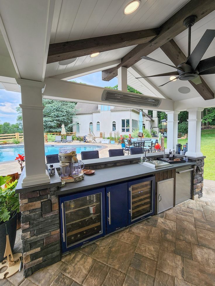 an outdoor kitchen with grills and tables on the outside patio overlooking a lake or golf course