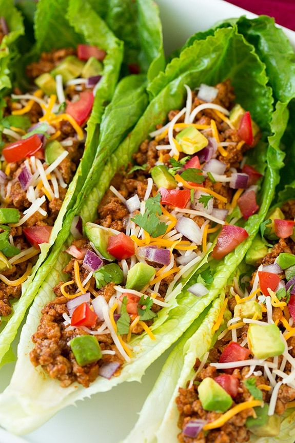 lettuce wraps filled with ground beef, cheese, and other toppings on a white plate