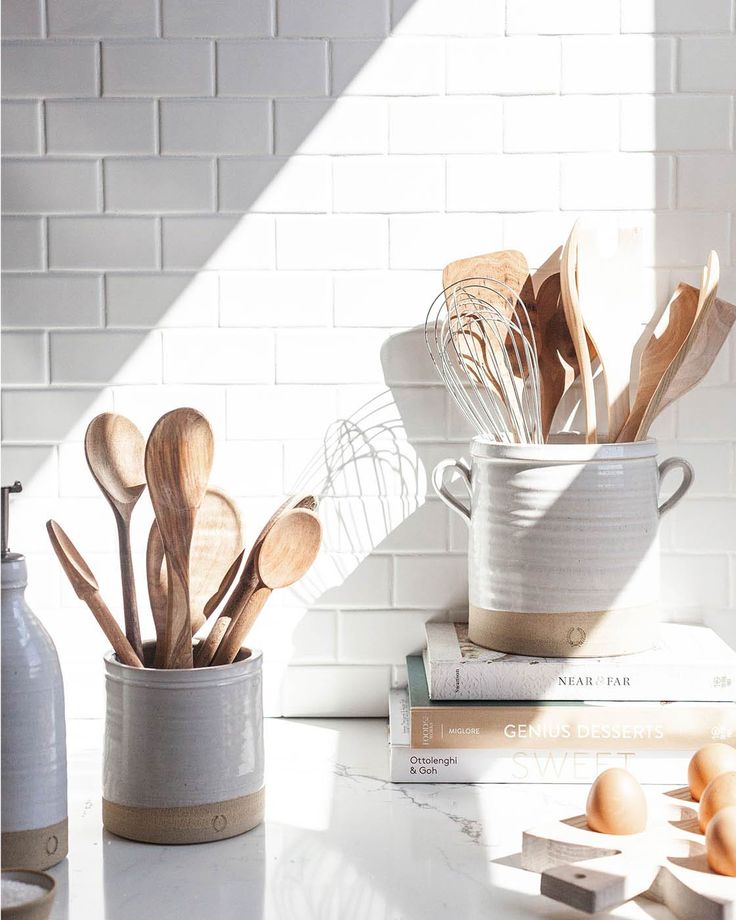 kitchen utensils and wooden spoons are on the counter next to some books