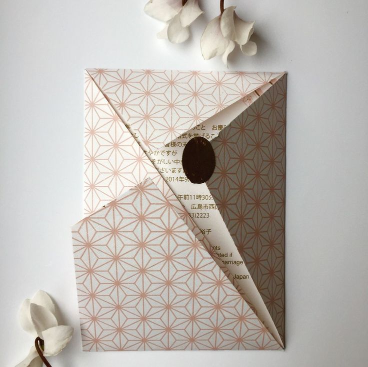 an origami envelope with a hole in it and flowers on the table next to it