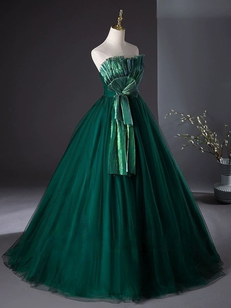 Step into a world of glamour with our Emerald Green Ball Gown with Luminous Pleated Accents - Green Evening Dress Plus Size. Crafted from rich, emerald fabric, this gown features a fitted bodice that gracefully transitions into a voluminous pleated skirt, creating a striking silhouette that commands attention. The pleats are intricately designed to catch and reflect light, giving the gown a luminous quality that enhances its luxurious appeal. Perfect for formal events or as an unconventional bridal option, this dress is designed to ensure you shine throughout the evening. With its perfect fit and exquisite detailing, it offers both comfort and elegance, making every moment unforgettable. Green Ball Gown With Fitted Bodice For Prom Season, Green Ball Gown With Fitted Bodice, Green Ball Gown With Fitted Bodice For Evening, Green Tulle Ball Gown For Banquets, Elegant Green Tulle Ball Gown, Green Tulle Ball Gown For Banquet, Dark Green Evening Dress For Prom Season, Green Gown With Fitted Bodice For Banquet, Green Ball Gown Evening Dress With Fitted Bodice