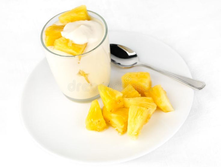 a white plate topped with sliced pineapple next to a cup of yogurt