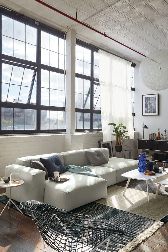 a living room filled with lots of furniture next to large windows and a rug on the floor