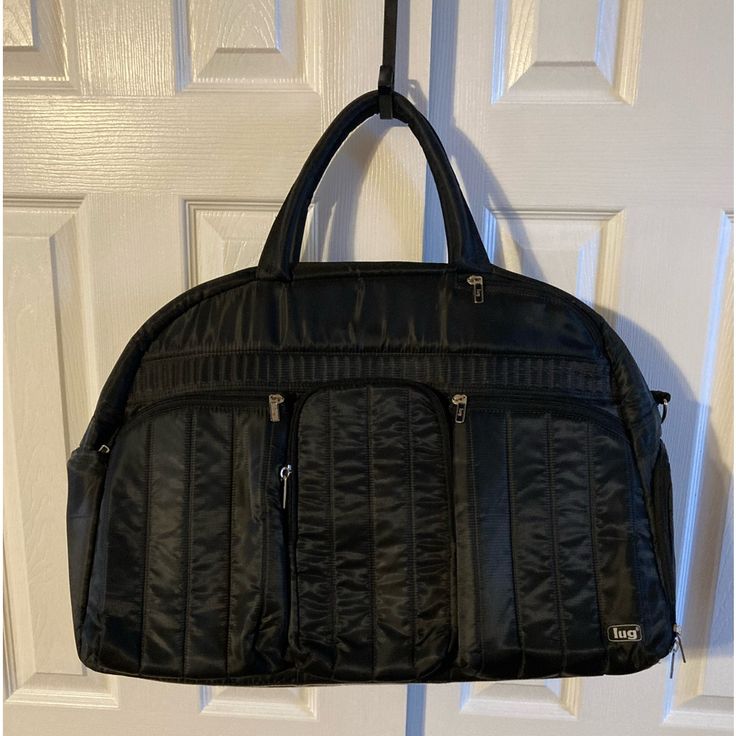 Lug Black Oversized Quilted Front Airbus Travel Bag. 3 Zip Pockets In The Front, 1 Very Large Zipper In The Back, 1 Zipper & Elastic Pocket On Side And 1 Large Mesh Zipper Shoe Pocket On Other Side. There Is Also 2 Large Elastic Pockets On One Inner Wall And 1 Large Zipper Pocket On The Other Inside Wall. There Is Room To Carry And Store So Many Items In This Carry On Oversized Bag. 100% Polyester Which Can Easily Be Wiped Clean. Approximately 19 3/4”W X 14”H X 9”D With A Handle Drop Of 5 1/2”. Black Travel Bag With Removable Pouch, Black Travel Bag With Removable Pouch For Trips, Black Double Handle Bag For Overnight Trips, Black Luggage With Removable Pouch For Trips, Black Duffle Bag With Removable Pouch For Trip, Versatile Black Bag For Trips, Versatile Black Bags For Trips, Black Shoulder Weekender Bag For Overnight Trips, Black Tote Weekender Bag For Trip