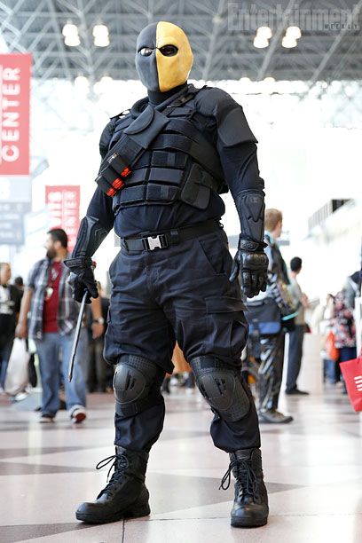 a man dressed as a masked soldier stands in an airport terminal while people look on