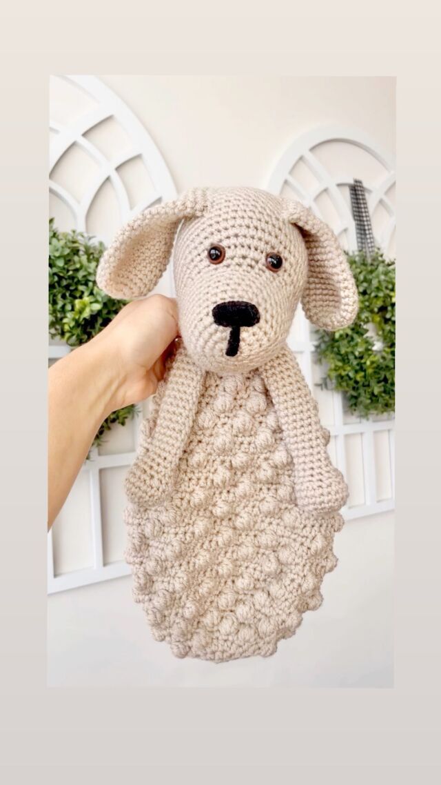 a crocheted stuffed animal is being held up by someone's hand in front of a white wall