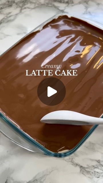 a chocolate cake in a glass pan with a white spatula sticking out of it