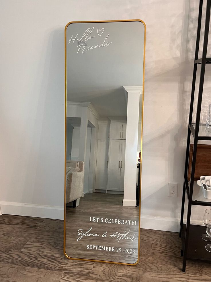 a large mirror sitting on top of a hard wood floor next to a white wall