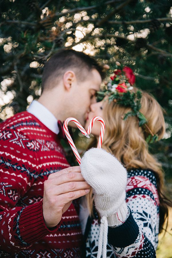 a man and woman kissing while holding candy canes