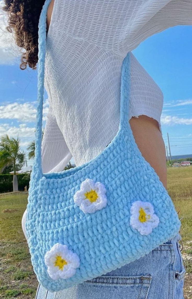 a woman is holding a crocheted bag with flowers on the front and side