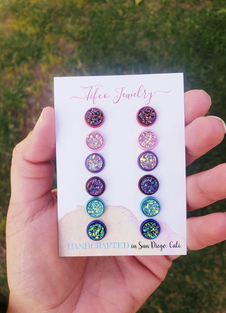 These Faux Druzy Earring Studs are absolutely gorgeous and made with high quality materials, just read our raving reviews from customers! They are lightweight, one-of-a-kind designed by me and Addy, unique, eye-catching, and beautiful. They shine and shimmer from every angle! The perfect birthday gift, or everyday wear! This is a 6 earring palette set. And comes with the following colors; -Berry rose gold - Rose Gold, Raspberry & gold colored druzy, set in a rose red earring post. -Light pink & light pink iridescent druzy set in a light pink earring post -Magenta -Magenta druzy with copper & slate blue notes, set in a red wine earring setting -Blue crystal -blue druzy with green & yellow notes, set in a blue earring setting -Lavender -purple lavender iridescent druzy, set in a light purple Nickel-free Multicolor Earrings For Birthday, Multicolor Round Earrings For Birthday, Multicolor Jewelry With Matching Earrings For Birthday, Multicolor Hypoallergenic Jewelry For Birthday, Hypoallergenic Multicolor Jewelry For Birthday, Purple Hypoallergenic Jewelry For Birthday, Adjustable Hypoallergenic Earrings For Birthday, Hypoallergenic Round Earrings For Birthday, Earring Stud Set