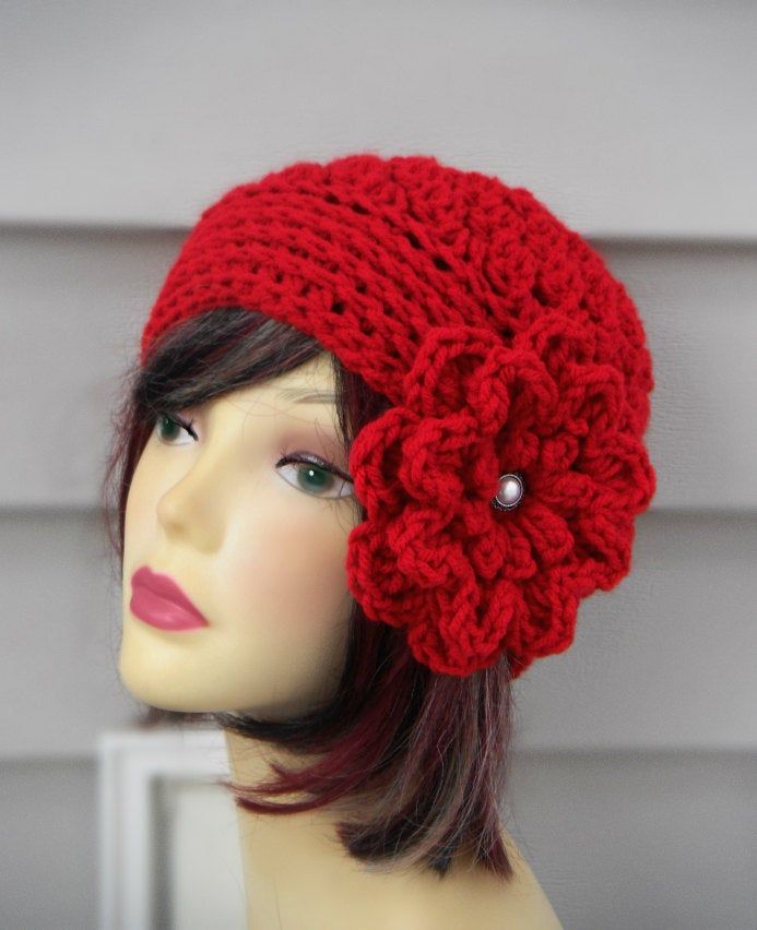 a mannequin head wearing a red knitted hat with a flower on it