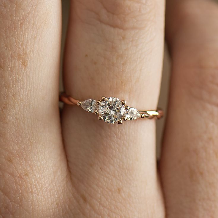 a woman's hand with a three stone diamond ring on her left hand,