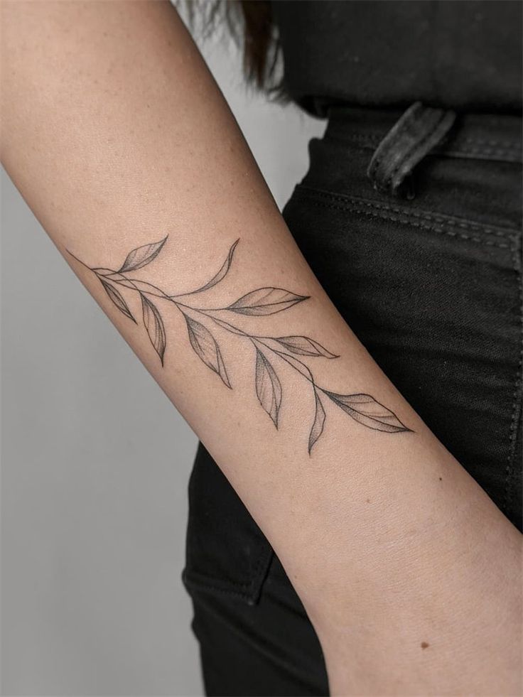 a woman's arm with a tattoo on it that has leaves growing out of it