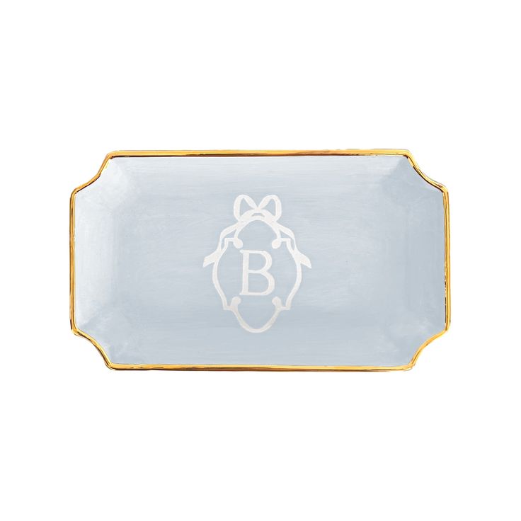 a white and gold tray with a monogrammed b on the bottom, in front of a white background