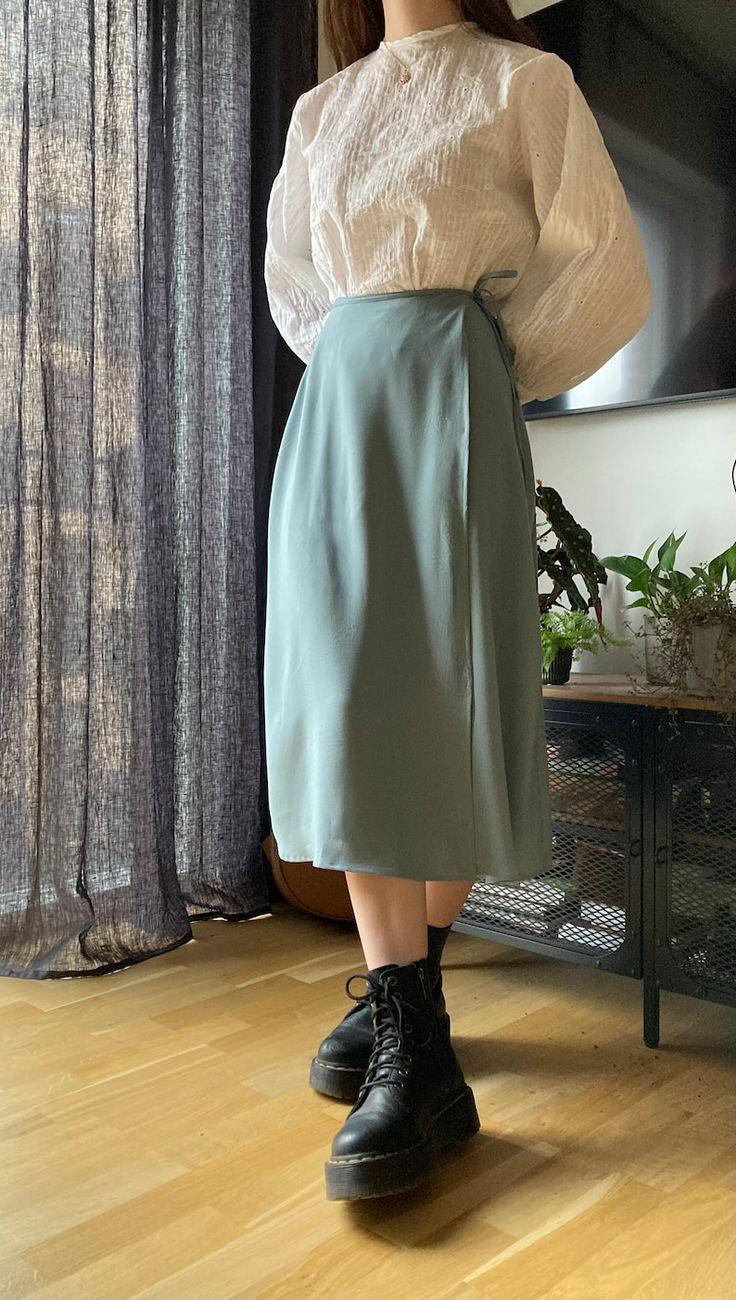 a woman standing in front of a window wearing a skirt