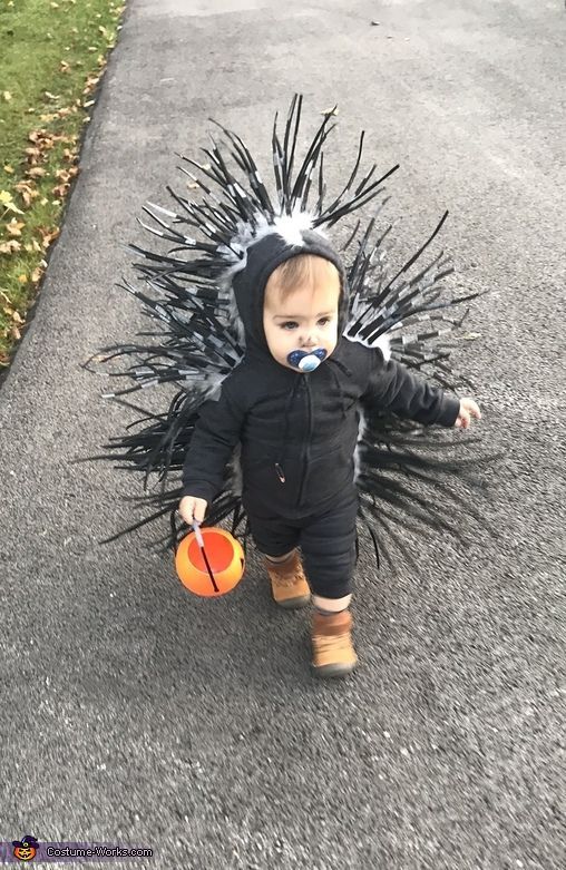 a toddler in a costume walking down the street with an orange ball and brush on his face