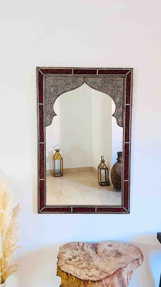 a mirror hanging on the wall next to a table with a stool in front of it