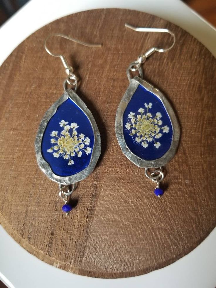 Real, beautiful and elegant Queen Anne's Lace has been pressed and dried. Sealed with beautiful shiny electric blue background and dangling blue lapis lazuli stones. No lead, no nickel! Super lightweight and flowy. Each pair will be made to order, they will all be unique and slightly different but similar design to the photographs! Handmade Blue Long Drop Jewelry, Handmade Blue Teardrop Jewelry, Silver Teardrop Earrings With Pressed Flowers, Elegant Lapis Lazuli Earrings For Gift, Blue Soldered Dangle Jewelry, Blue Teardrop Jewelry With Pressed Flowers, Blue Lapis Lazuli Dangle Jewelry, Blue Teardrop Pressed Flower Jewelry, Blue Pressed Flowers Drop Earrings