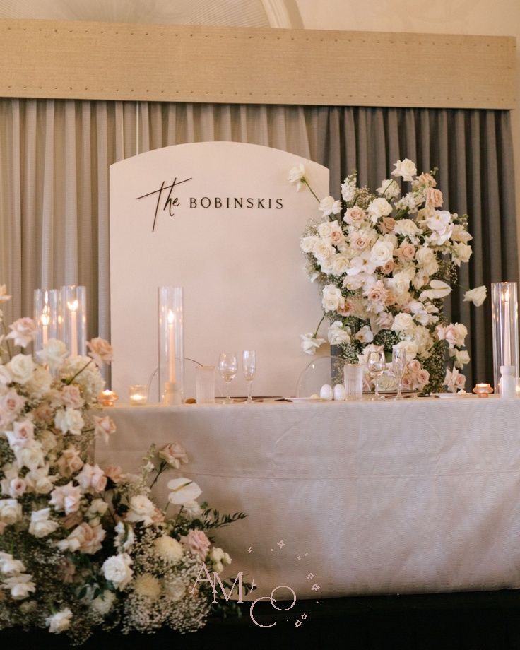 a table with flowers and candles on it next to a sign that says the bokinskis