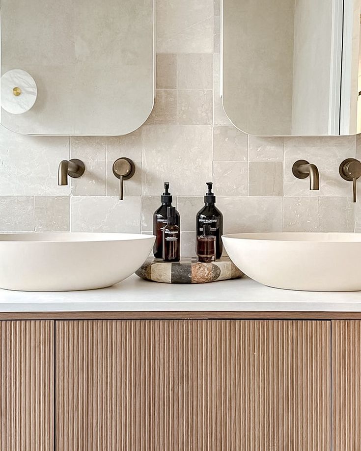 two white sinks sitting next to each other on top of a wooden cabinet in a bathroom