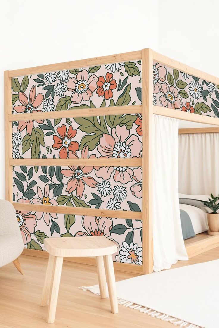 a bedroom with floral wallpaper on the walls and wooden flooring, along with a white chair