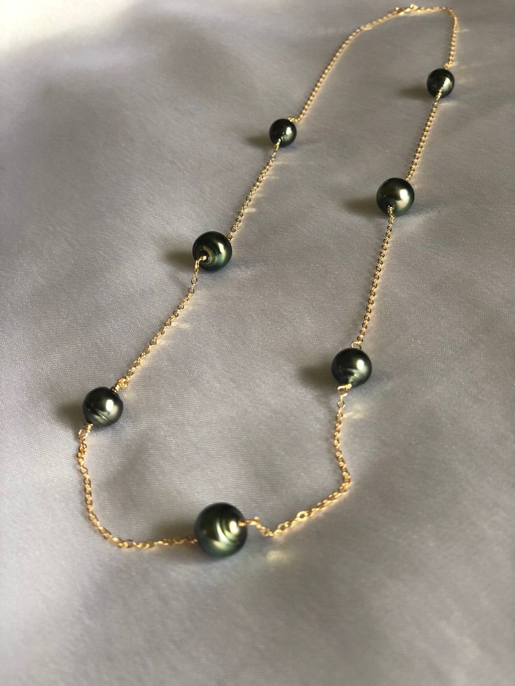 LEIMOMI. 7 beautifully placed Tahitian black cultured pearls flowing gracefully amongst a simple, yet dainty chain necklace. Pearls are 8.5 and 9.5mm. Cable chain is 14K gold filled, 24 inches in length. Each piece from my collection is handmade, designed and crafted by me. The Tahitian pearl is so beautiful and has always been my most favorite jewel, so most of my line includes a unique pearl of its own. I use a high quality soft and delicate gold-filled metal that won't tarnish during everyday Formal Tahitian Pearl Necklace In Yellow Gold, Formal Yellow Gold Tahitian Pearl Necklace, Elegant Gold Tahitian Pearl Necklaces, Elegant Gold Tahitian Pearl Necklace, Classic Tahitian Pearl Drop Necklaces, Gold Tahitian Pearl Single Strand Necklace, Yellow Gold Tahitian Pearl Necklace, Classic Gold Tahitian Pearl Necklace, Classic Gold Jewelry With Tahitian Pearl