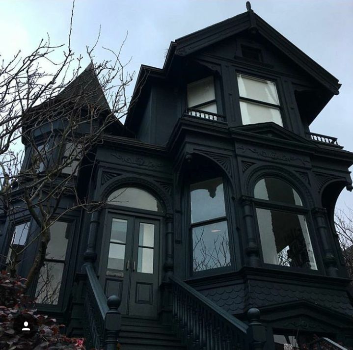 an old black victorian style house with large windows