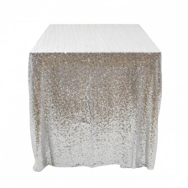 a table covered in silver sequins on top of a white tablecloth with gold trim