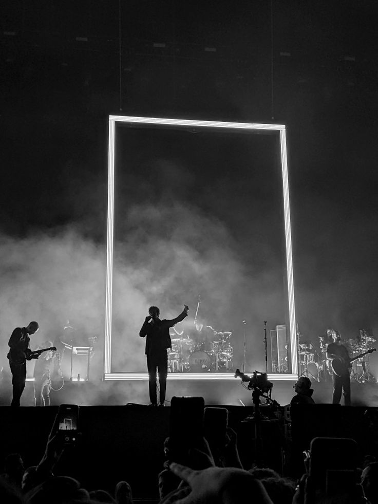 three people are standing on stage with their arms out in front of an empty screen