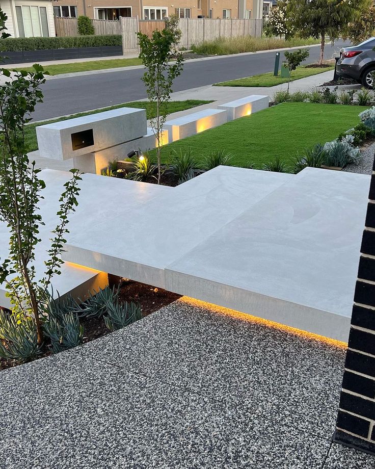 an outdoor garden area with concrete steps and plants on the side of the road in front of a building