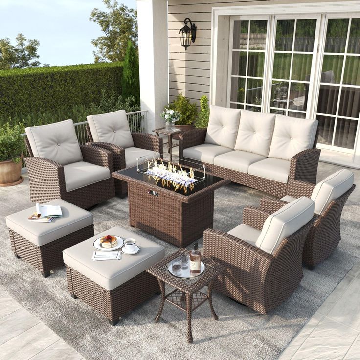 an outdoor living room with wicker furniture and glass top fire pit in the center