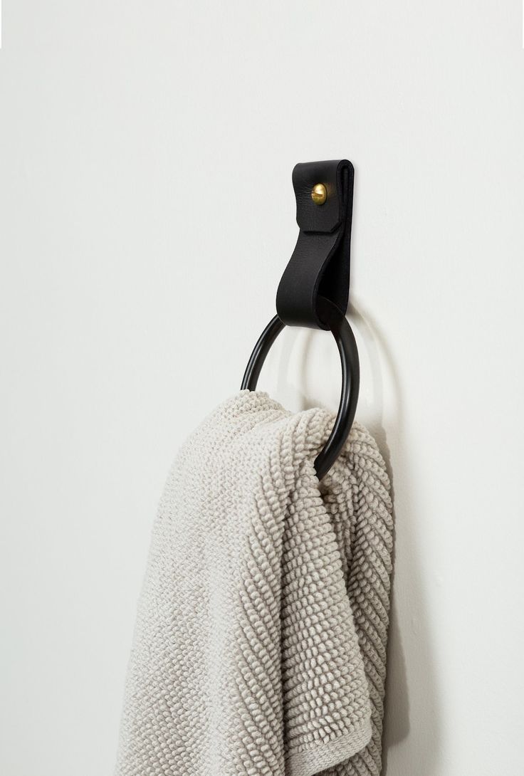 a towel hanging on the wall with a black hook in front of it and a white background