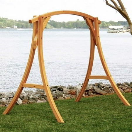 a wooden swing set sitting on top of a lush green field next to a lake