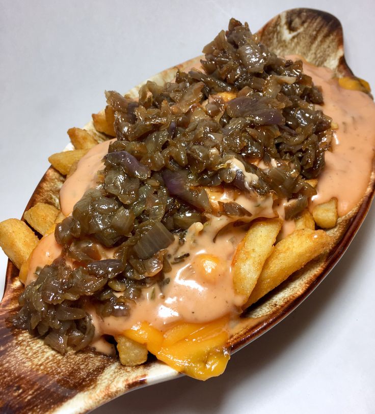 a close up of a hot dog with toppings on it and french fries in the foreground