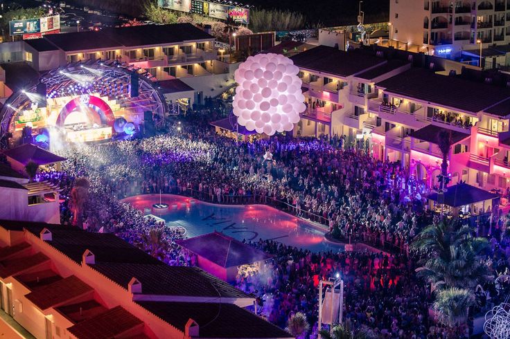 an aerial view of a city at night with balloons being flown in the air and onlookers watching