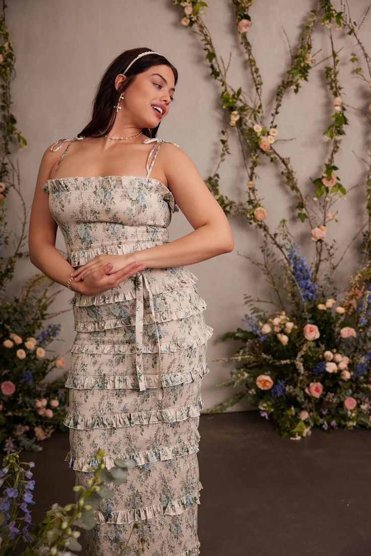 a woman standing in front of flowers wearing a dress