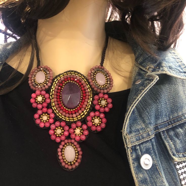 a woman wearing a black shirt and pink beaded necklace on top of a mannequin