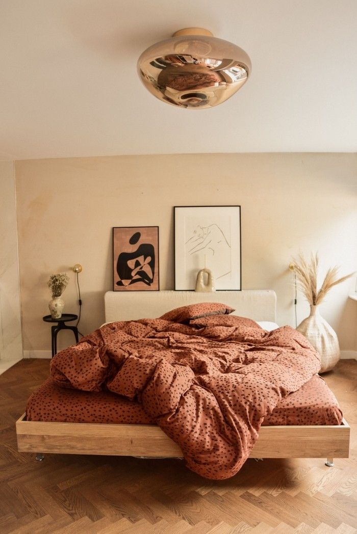 a bed sitting on top of a hard wood floor next to a wall with pictures above it