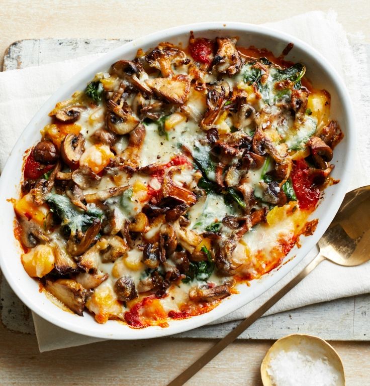 a casserole dish with mushrooms, cheese and spinach on a white napkin