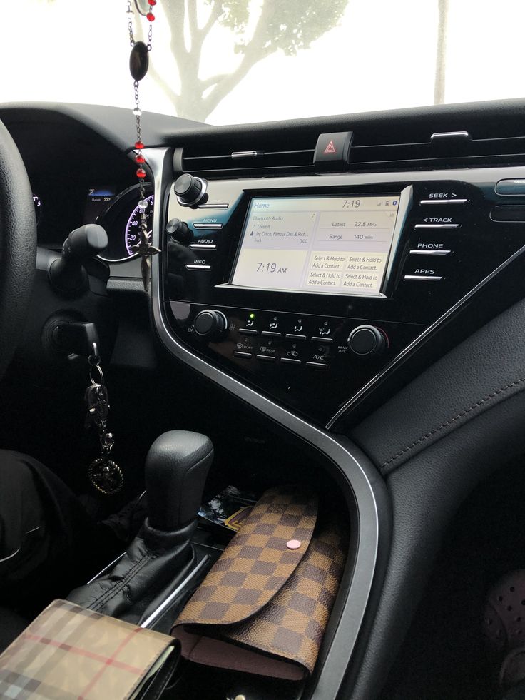 the interior of a car with an electronic device and other items hanging from it's dashboard