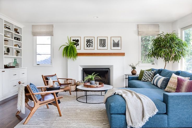 a living room filled with furniture and a fire place under a window next to a potted plant