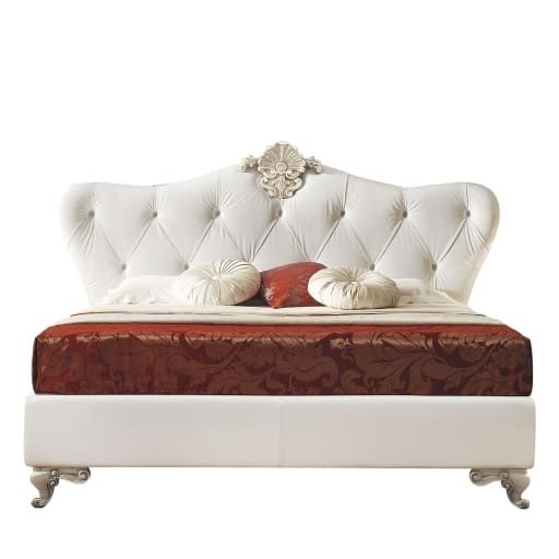 a white bed with two pillows on top of it and a red pillow underneath the headboard