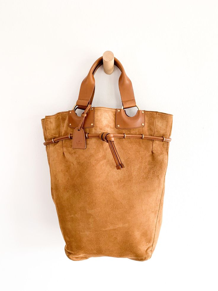 Classic suede and leather rich warm tan Gucci tote bag. Attached small pouch makes finding essentials easier. 16"(h) x 4"(d) x 9"(w at base)/14"(w at top)Handle drop 5"Attached leather pouch 5 1/2"(h) x 4 3/4"(w) Condition: Very good. Leather cinch showing areas of dryness. Gucci Shoulder Satchel For Everyday Use, Gucci Satchel Shoulder Bag For Daily Use, Gucci Satchel For Everyday Use, Gucci Shoulder Bag Satchel For Daily Use, Gucci Soft Leather Shoulder Bag For Daily Use, Daily Use Gucci Soft Leather Shoulder Bag, Gucci Brown Satchel Bag, Gucci Tote Shoulder Bag With Removable Pouch, Gucci Tote With Removable Pouch