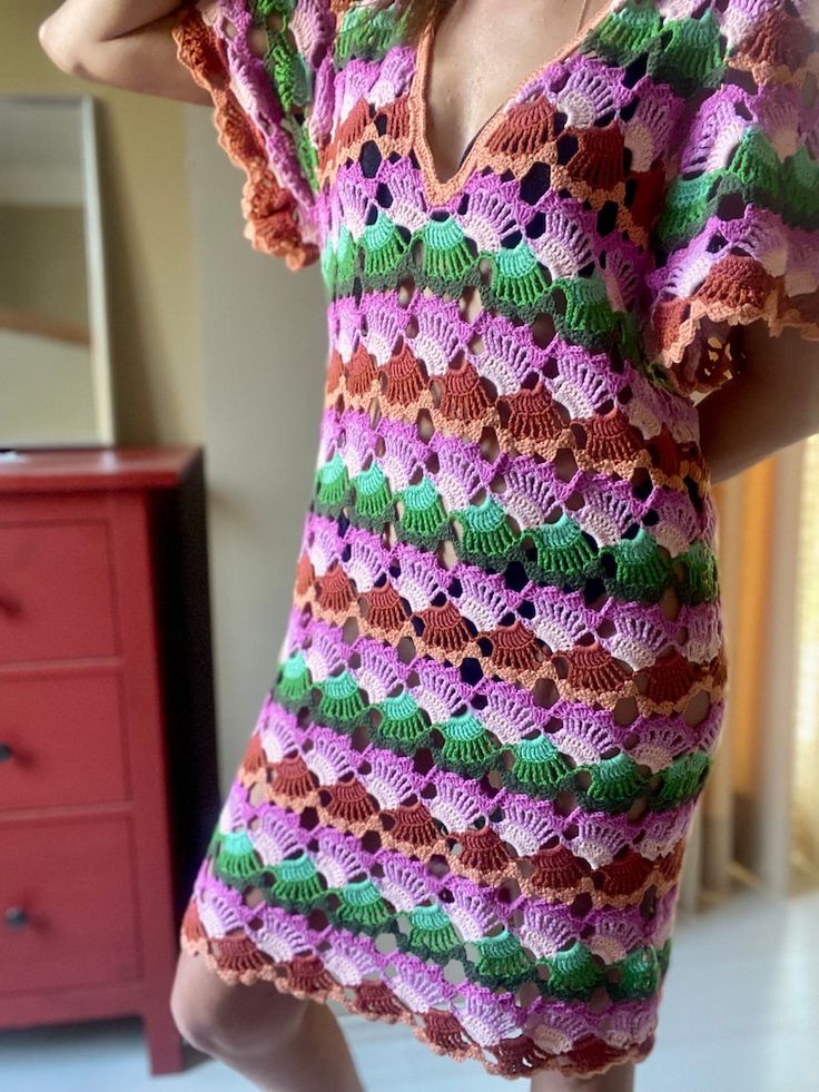 a woman in a crocheted dress posing for the camera with her hand on her head