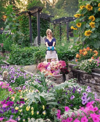 a woman standing in a garden filled with lots of flowers