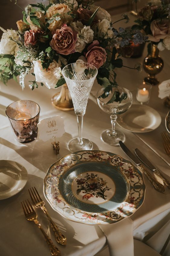 the table is set with plates, silverware and floral centerpieces on it