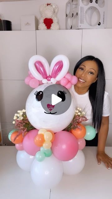 a woman is posing next to an inflatable balloon bunny with flowers and balloons