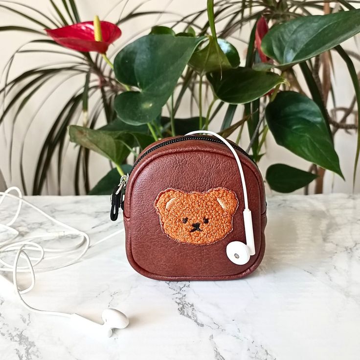 a brown teddy bear purse with headphones attached to it