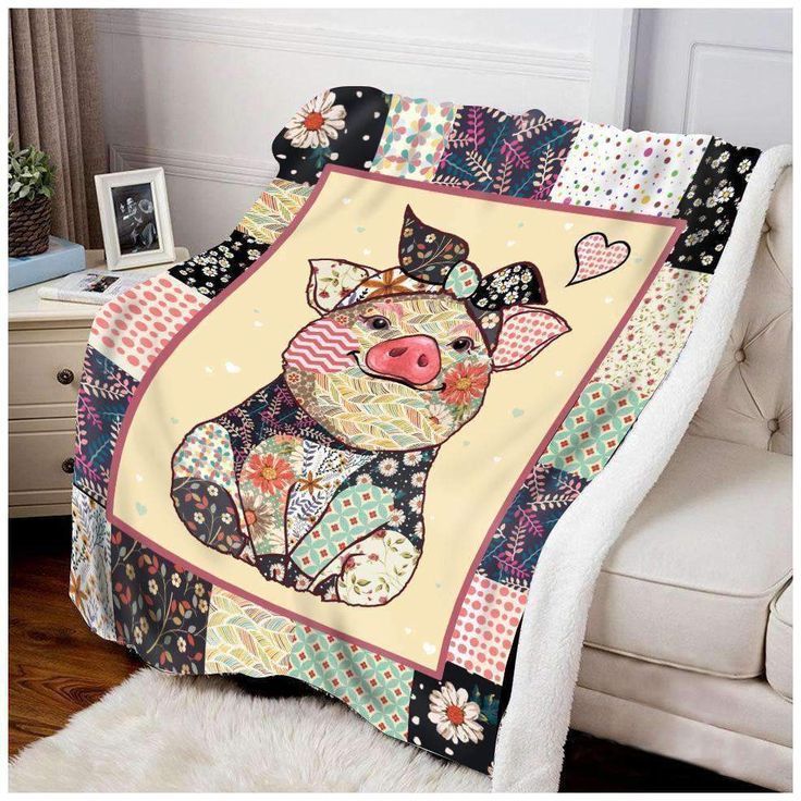 a blanket with a pig on it sitting in front of a white chair next to a window